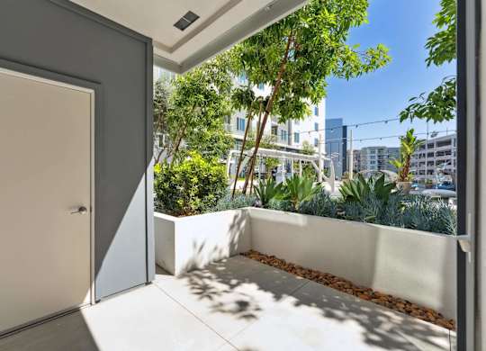 A white door is open to a balcony with a view of a cityscape.