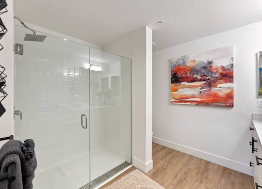 A bathroom with a glass shower door and a towel hanging on a rack.