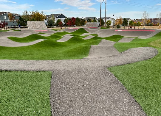A skate park with a concrete path and green grass.