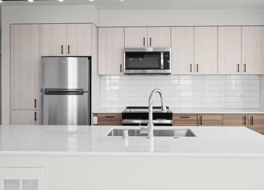 a kitchen with white countertops and white cabinets with a stainless steel refrigerator and microwave at Ion Town Center, Washington