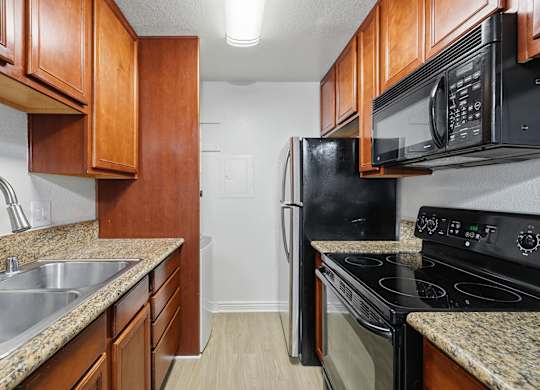 A kitchen with black appliances and wooden cabinets.