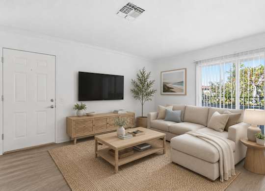 A spacious living room wit a wooden coffee table, white sofa, and a flat-screen