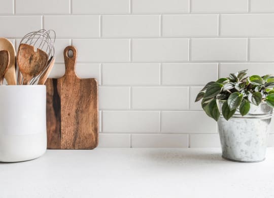 a kitchen counter with wooden utensils and a potted plant