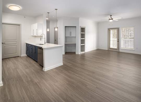 an empty living room with a kitchen and a door to a closet