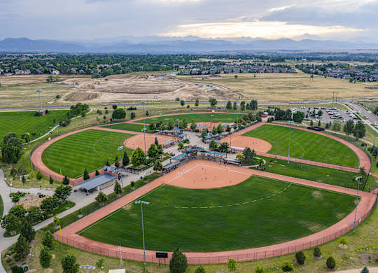 A large, open athletic track with a red track surface and a green grass field surrounding it.
