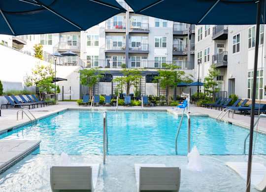 A large outdoor swimming pool with lounge chairs and umbrellas.