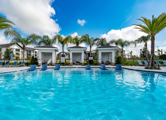 a large swimming pool with palm trees and condos in the background