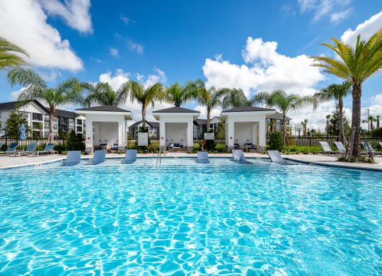 a large swimming pool with palm trees and buildings in the background