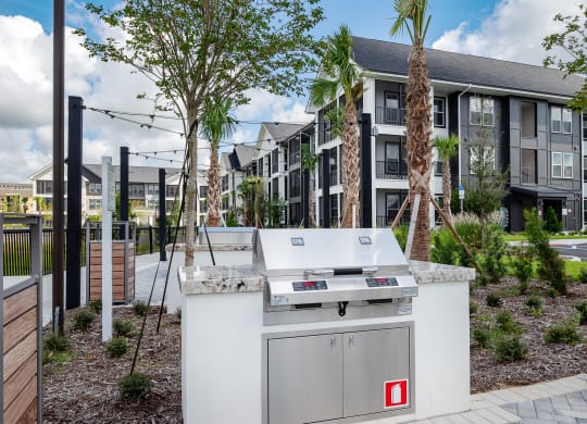 an outdoor kitchen with a grill in front of an apartment building