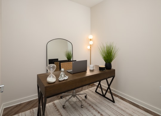 a bedroom with a desk with a laptop and a mirror