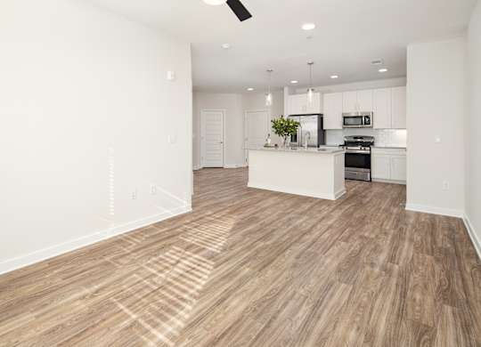 an open kitchen and living room with white walls and wood flooring
