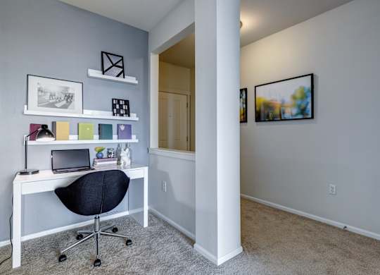 a home office in a bedroom with gray walls and carpet