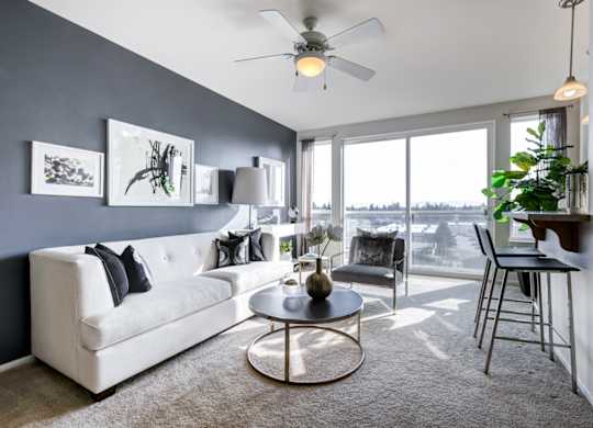 a living room with a large window and a ceiling fan
