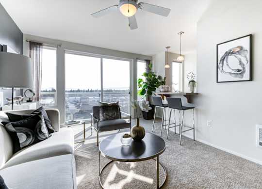 a living room with a large window and a ceiling fan