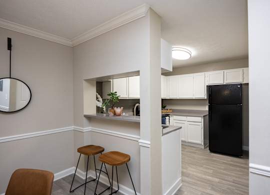 A kitchen with a black fridge and white cabinets.