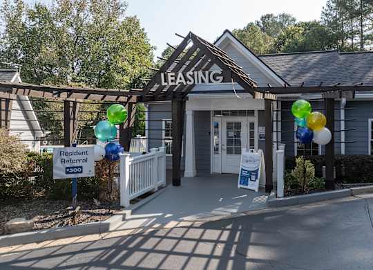 A leasing office is surrounded by balloons and a sign advertises a resident referral.