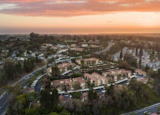 A sunset view of a residential area with houses and trees.