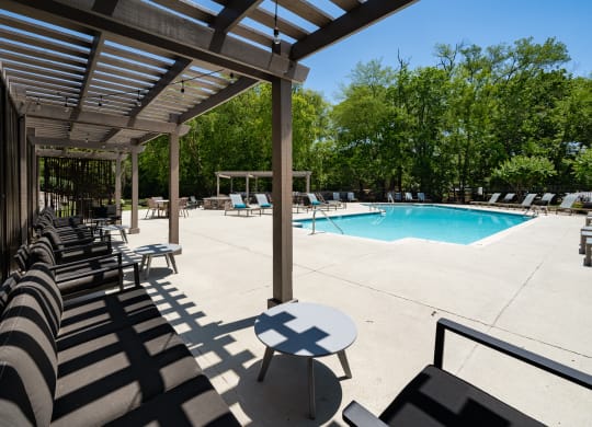 a pool with lounge chairs and a table in the shade