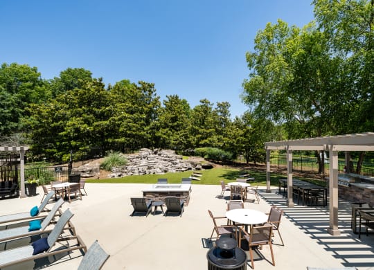a patio with tables and chairs and a grassy area with trees