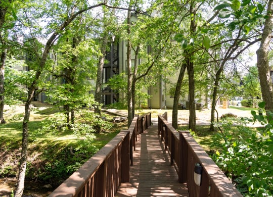 a wooden bridge in the middle of a park with trees