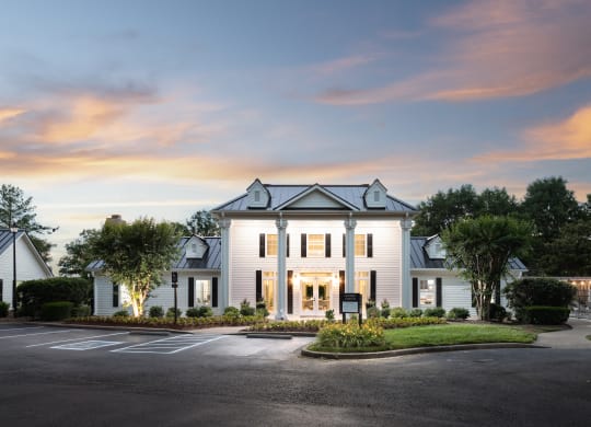 a white house with a parking lot and a sunset in the sky