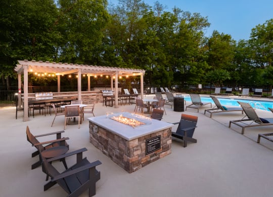 a patio with a fire pit and a pool with chairs and tables