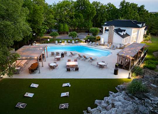 a backyard with a pool and a patio with tables and chairs