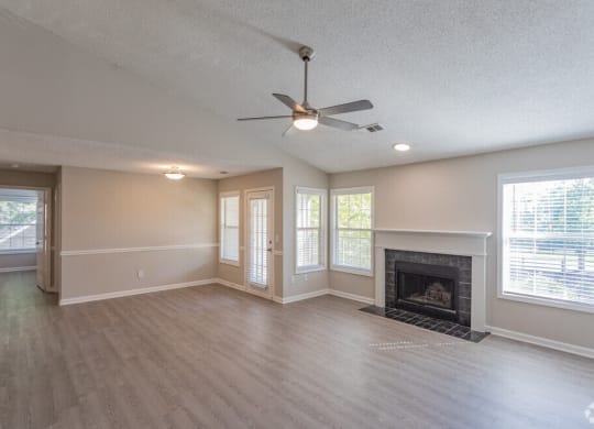 an empty living room with a fireplace and a ceiling fan