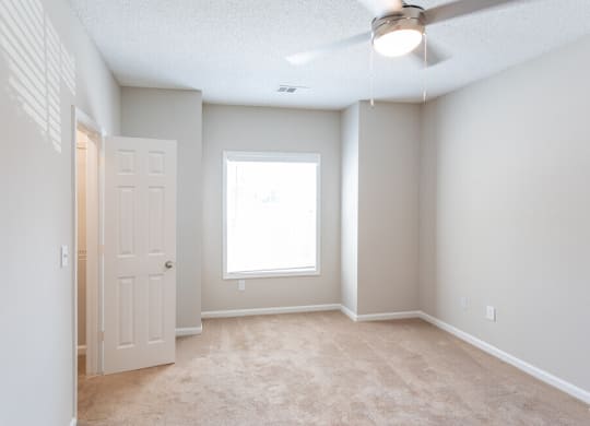 an empty room with a white door and a window