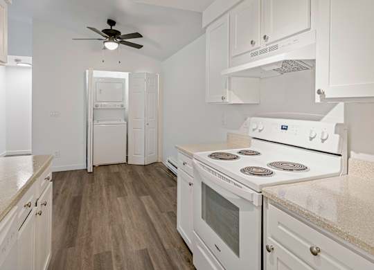A white kitchen with a fan and a stove top oven.