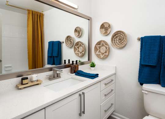a bathroom with white cabinets and a mirror and a toilet and a sink