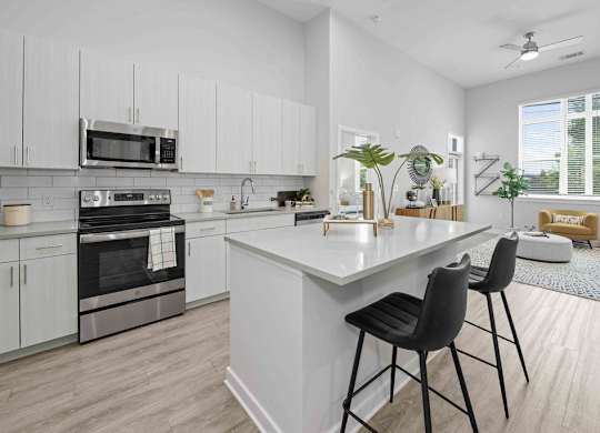 A modern kitchen with white cabinets and a large island.