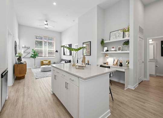A well-lit, modern kitchen with white cabinets and a wooden floor.