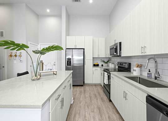 A modern kitchen with white cabinets and a marble countertop.