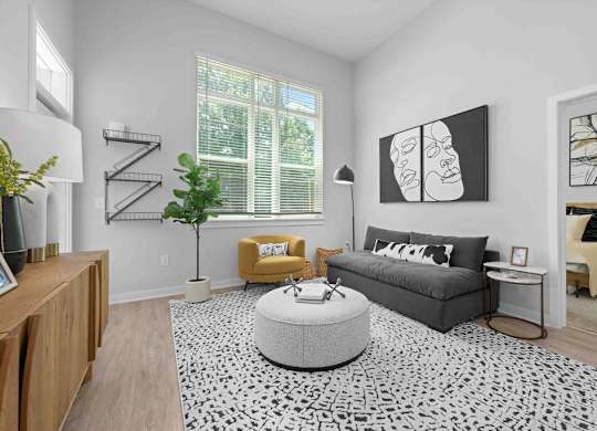 A living room with a grey sofa, yellow armchair, and a black and white patterned rug.