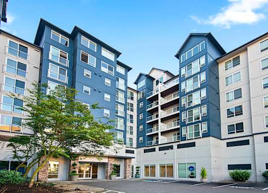 an exterior view of an apartment building with a tree in the courtyard