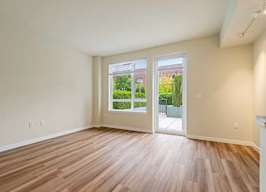 A room with wooden flooring and a view of a garden through the window.