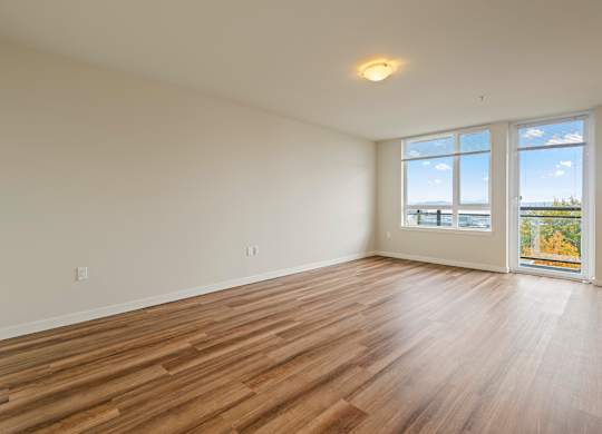 A room with wooden flooring and a large window overlooking the ocean.