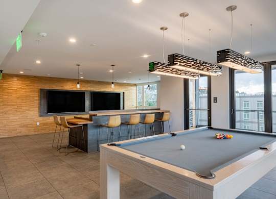 A billiard table is in the middle of a room with a brick wall and a television.at Axle, Seattle, WA 98119 