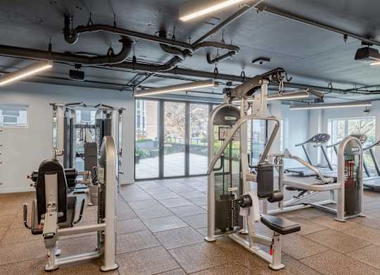 A gym with a variety of equipment including a leg press machine and a treadmill.at Axle, Seattle 