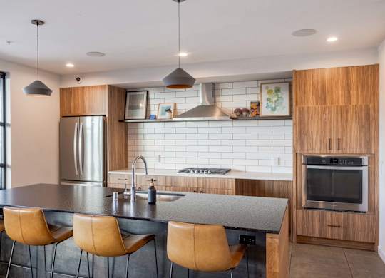 A modern kitchen with a stainless steel refrigerator, a wooden cabinet, and a black countertop.at Axle, Seattle, 98119 
