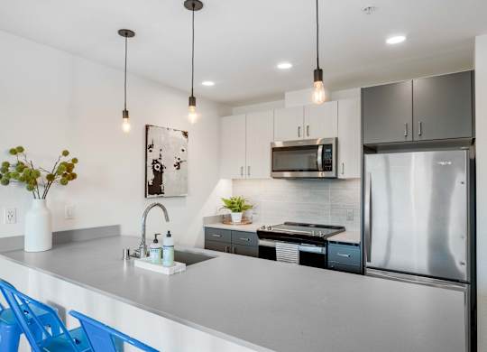 A modern kitchen with a stainless steel refrigerator and blue chairs.at Axle, Seattle 