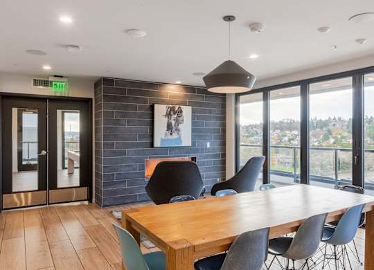 A conference room with a long table and chairs, a fireplace, and a view of the outdoors through large windows.at Axle, Seattle, WA 