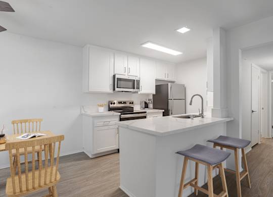 A modern kitchen with a white island and wooden stools.