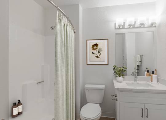 A white bathroom with a toilet, sink, and shower.