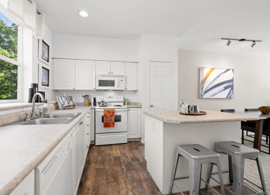 a kitchen with white cabinets and a large window