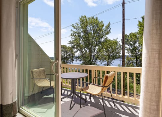 a balcony with a table and two chairs and a view of the water