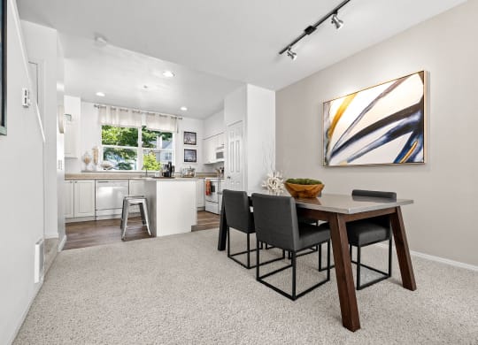 a dining area with a table and chairs and a kitchen in the background
