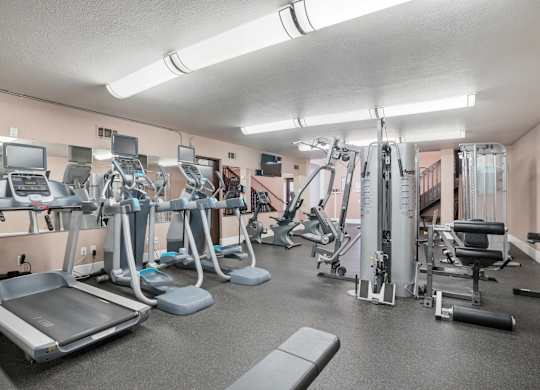 A gym with a variety of equipment including treadmills, weights, and exercise machines.