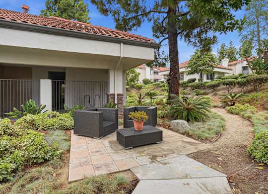 A patio with a table and chairs is surrounded by a garden.